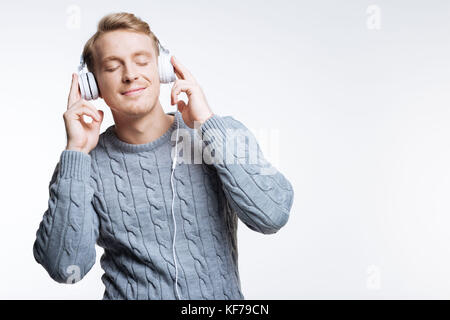 Blonde junge Mann Hören von Musik über Kopfhörer Stockfoto