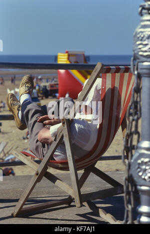 Reifer mann Entspannen im Liegestuhl entlang der Promenade von Blackpool, Lancashire, England, Großbritannien Stockfoto