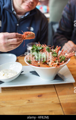 Kanada, Vancouver, British Columbia, ein Mann, der gebratene Garnelen Köpfe an einem lokalen Bistro isst, essbare Kanada, auf Granville Island entfernt Stockfoto