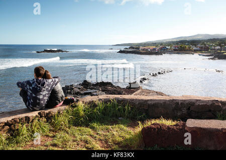 Easter Island, Chile, Isla de Pascua, Rapa Nui, ein Paar sitzt und beobachtet die Brandung in der Nähe von Hanga Roa kommen Stockfoto