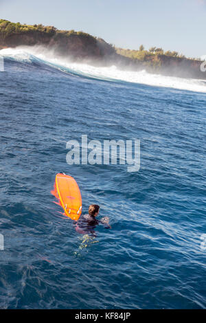 USA, HAWAII, Maui, Jaws, Big-Wave-Surfer, der mit seinem Board ins Wasser springt, während er auf dem Sprung ist, um Peahi an der Nordküste zu surfen Stockfoto