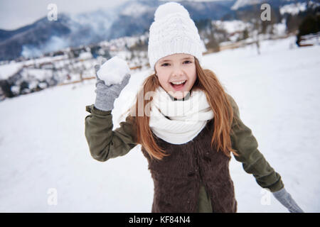 Mutwillige Mädchen mit Schneeball in der Hand Stockfoto