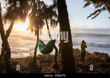 Hawaii, Oahu, North Shore, Umstehende sehen Sie eine große Rolle in Schwellen bei Sonnenuntergang an pupukea Beach Park an der Nordküste Stockfoto