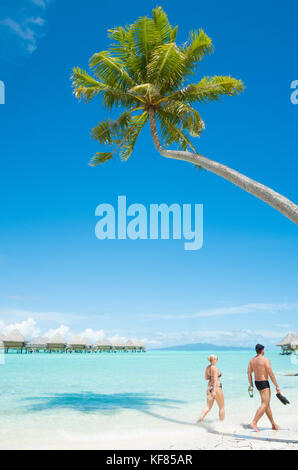 Zwei Gäste machen einen Strandspaziergang im Intercontinental Le Moana Resort in Bora Bora, Französisch-Polynesien Stockfoto