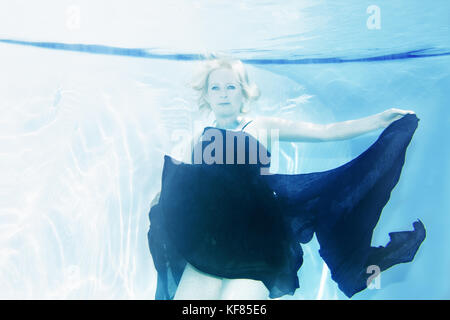 Europa, Spanien, Balearen, Mallorca, einen Pool im Canyamel - eine Frau unterwasser Floating mit blauem Kleid Stockfoto