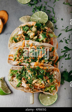 Frischer Fisch Tacos mit Salat, Tomaten, Zwiebeln, Avocado, garniert mit Schichten aus Kalk und viel Koriander Stockfoto