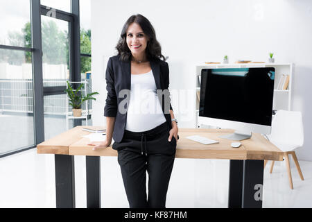 Schwangere Geschäftsfrau lehnte sich zurück auf Arbeitstisch Stockfoto