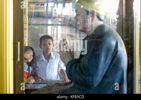 Myanmar (früher Birma). Yangon (Rangoon). Kyaukhtatgyi Pagode. Junge Kinder in der Bewunderung vor einer Statue Stockfoto