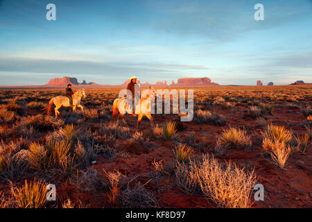 Usa, Arizona, Utah, Monument Valley, Navajo Tribal Park, ein Navajo Mann und sein Sohn reiten, in Richtung des bringham Grab in Utah suchen Stockfoto