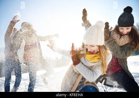 Jungs das Werfen mit Schneebällen auf die Mädchen Stockfoto