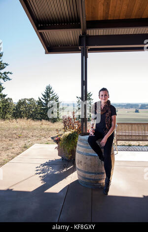 Usa, Oregon, Willamette Valley, Portrait von eine schöne junge Frau mit einem Glas Rotwein in der probierstube an sotor Weinberge und Weinkeller, carlto Stockfoto