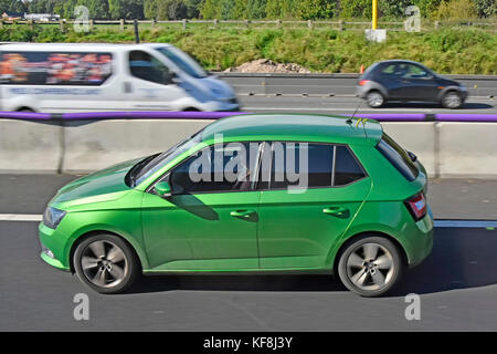 Grüne Limousine Auto entlang fahren Lane drei der britischen Autobahn mit temporären Schnitt konkrete Leitplanken bei Straßenarbeiten Frau Beifahrer im Auto. Stockfoto