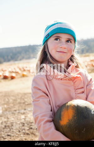 Usa, Oregon, Biegen, ein junges Mädchen, findet einen Kürbis home bei der jährlichen Pumpkin Patch in terrebone nearcsmith Rock State Park zu nehmen Stockfoto