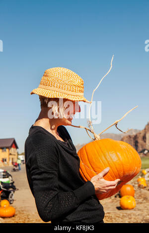 Usa, Oregon, Bend, eine Frau entscheidet, ein Kürbis auf dem jährlichen Pumpkin Patch in der Nähe von terrebone Smith Rock State Park Stockfoto