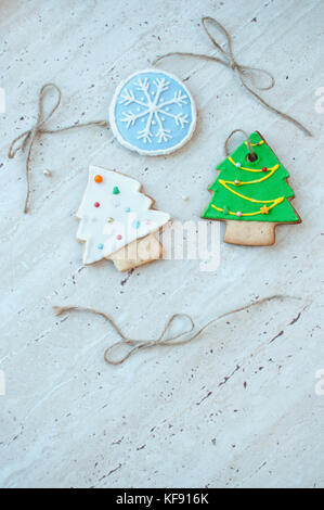 Zwei Lebkuchen Kekse in der Form der grünen und weißen Weihnachtsbaum und ein Keks in der Form eines runden blauen Schneeflocke auf dem Hintergrund einer hölzernen Tisch. Stockfoto