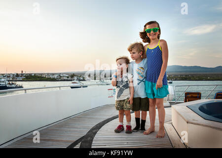 Galapagos, Ecuador, junge Kinder an Bord der M/c Ocean Spray in der Nähe von Santa Cruz Insel hängen Stockfoto