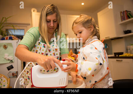 Mutter und Tochter das Mischen von Zutaten in der Vorbereitung für das Backen eines Kuchens Stockfoto