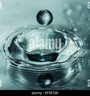 Eine Makroaufnahme eines Wassertropfens über in ein Loch von einem anderen Wasser Tropfen zu fallen. Stockfoto