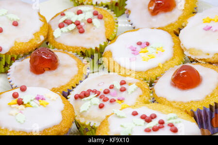 Eine Nahaufnahme eines hausgemachten Cupcakes mit Zuckerglasur, Gletscher Kirschen und Streuseln. Stockfoto