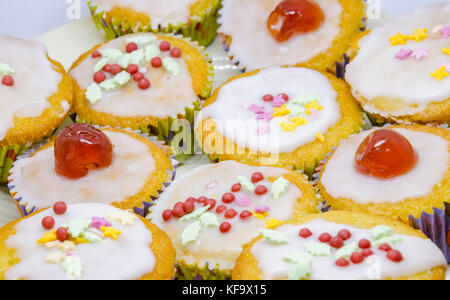 Eine Nahaufnahme eines hausgemachten Cupcakes mit Zuckerglasur, Gletscher Kirschen und Streuseln. Stockfoto