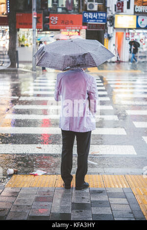 Koreanische Leute warten an einem Quersteg im Regen Stockfoto