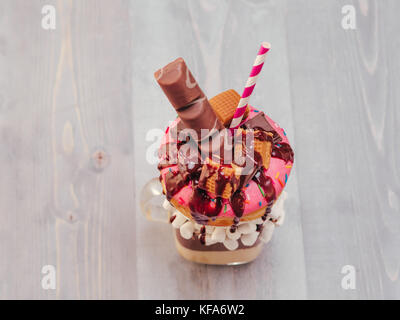 Schokolade Donuts und extreme Milchshake mit Marshmallow und andere Süßigkeiten in Mason jar auf grau Holz- Hintergrund. Crazy freakshake auf grau Holztisch Stockfoto