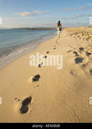 Frau zu Fuß durch das Meer ihre Fußspuren im Sand am Meer Strand Ses Illetes, Formentera (Balearen, Spanien) Stockfoto