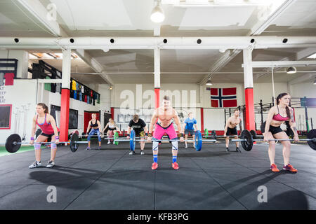 Bestimmt Trainer mit Athleten anheben Barbells in der Turnhalle Stockfoto