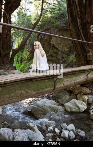 Usa, Kalifornien, Big Sur, Esalen, eine Frau sitzt auf einer kleinen Brücke über Hot Springs Creek am Esalen Institut Stockfoto