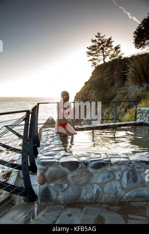 Usa, Kalifornien, Big Sur, Esalen, eine Frau sitzt in den Bädern und blickt auf die Big Sur Küste bei Sonnenuntergang, die esalen Institut Stockfoto