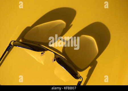 Abstrakte Darstellung von Sonnenlicht-Schatten auf gelbem Hintergrund einer Brille Stockfoto