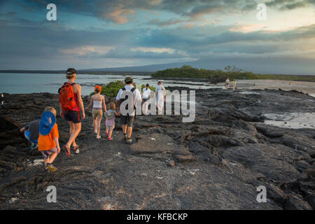 GALAPAGOS, Ecuador, eine Gruppe von Menschen heraus hängen am Strand und beobachten den Sonnenuntergang von Fernandina Insel Stockfoto