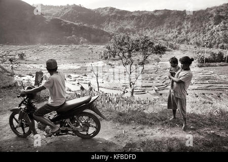 Indonesien, Flores, Menschen versammeln sich auf der Straße mit Blick auf ein Tal mit Reisfeldern und Arbeiter in der Ferne gefüllt, waturaka Dorf Stockfoto