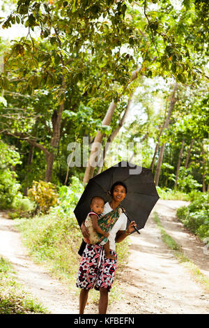 Philippinen, Palawan, Barangay Region, eine Frau und ihr Baby Schatten unter einem Sonnenschirm im kleinen Dorf Berg Purok tarabidan Stockfoto