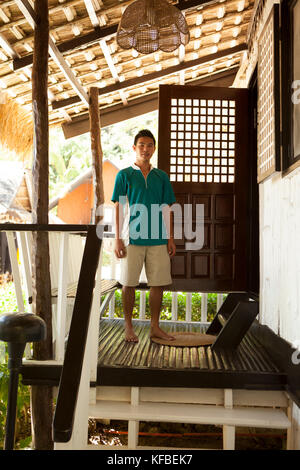 Philippinen, Palawan, El Nido, ein junger Mann steht vor einem der Cottages von Miniloc Island Resort, Bacuit Bucht in das Südchinesische Meer. Stockfoto