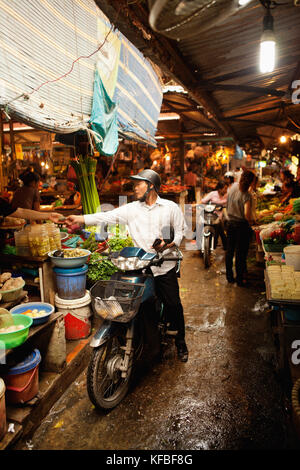 VIETNAM, Hanoi, Chau Long Markt, ein Mann reitet ihn durch den Markt Moped- und hält einige Kartoffeln kaufen Stockfoto