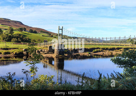 Zwei Wanderer Überquerung der Hängebrücke über den Fluss Swale in der Nähe von Reeth, North Yorkshire, England Stockfoto