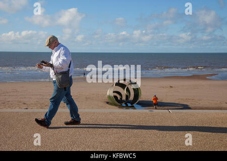 Cleveleys, Lancashire, UK. 27. Oktober, 2017. UK Wetter: Sonnig mit kräftigen Winde an Cleveleys. Das Sands rund um St Mary's Shell ein öffentliches Kunstwerk am nördlichen Ende der neuen Promenade. Es ist ein großes Stück von Kunst im öffentlichen Raum, mit einer Basis, die zu konkreten Stiftungen in der Strand festgesetzt wurde befestigt. Es ist 8 m lang und 4 m hoch und wiegt 16,5 Tonnen, mit Worten aus der Geschichte von das Meer Schlucken geätzt. Credit: MediaWorldImages/Alamy Leben Nachrichten. Stockfoto