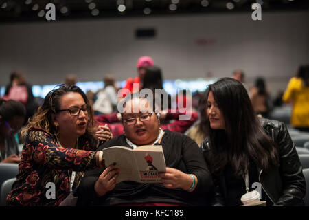 Detroit, Michigan, USA. Okt. 2017. Drei Teilnehmer des Frauenkonventes sehen sich nach der Begrüßungsveranstaltung Reclaiming Our Time im Cobo Center, Detroit Michigan, Freitag, 27. Oktober 2017 über das Conventions Programm. Credit: Theresa Scarbrough/Alamy Live News Stockfoto