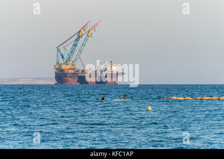 Die Bucht von Larnaca, Zypern. 27. Oktober, 2017. Personen Kajak im Mittelmeer und Blick auf Öl und Gas rigging Plattform in Zypern, Larnaca Bay. Saipem 7000 Verlegung von Krane Credit: RedNumberOne/Alamy Leben Nachrichten angedockt Stockfoto