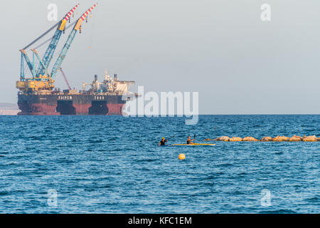 Die Bucht von Larnaca, Zypern. 27. Oktober, 2017. Personen Kajak im Mittelmeer und Blick auf Öl und Gas rigging Plattform in Zypern, Larnaca Bay. Saipem 7000 Verlegung von Krane Credit: RedNumberOne/Alamy Leben Nachrichten angedockt Stockfoto