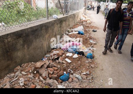 HYDERABAD, Indien - Oktober 22,2017. Menschen gehen auf einer Straße mit Bauschutt und Plastiktüten mit Hausmüll in Hyderabad gefüllt gesäumt, ICH Stockfoto