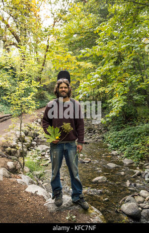 USA, Oregon, Ashland, Portrait von Carston Peer in Lithia Park mit Blumen und Blätter, die er gesammelt hat und in einem Kranz gewebt Stockfoto