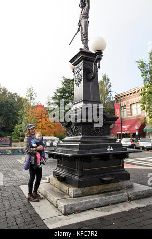 Usa, Oregon, Ashland, eine lokale Frau Dana steht mit ihrem Baby Olivia vor einer Skulptur auf dem Marktplatz in der Innenstadt von Ashland Stockfoto