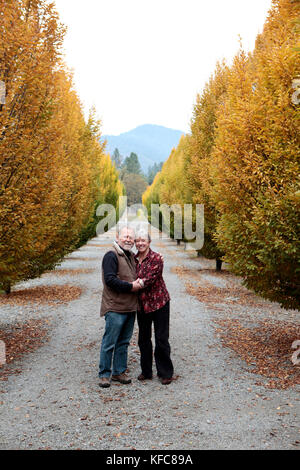 USA, Oregon, Medford, Cal und Judy Schmidt stand unter den Bäumen auf der Farm, Familie Schmidt Weinbergen im schönen Applegate Valley befindet. Stockfoto