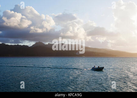 Französisch Polynesien, Vahine Island. Blick auf ein Boot und Tahaa Island im Hintergrund in der Abenddämmerung. Stockfoto