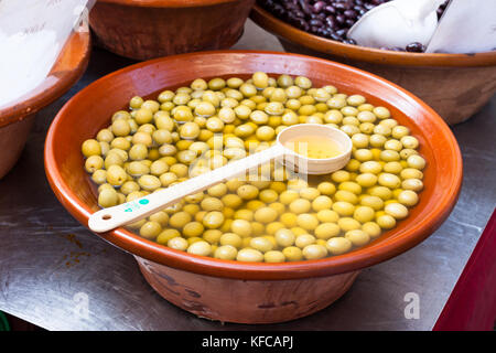 Eingelegte grüne Oliven für Verkauf in einem Kochen mit einem Löffel in Sineu Markt, Mallorca, Spanien Stockfoto