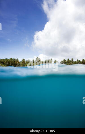 Indonesien, Mentawai Inseln, kandui Resort, im Indischen Ozean und eine Insel mit Palmen im Hintergrund gegen bewölkter Himmel Stockfoto