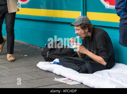 Obdachloser Verzehr einer Mahlzeit auf den Straßen in Brighton, East Sussex, England, UK. Stockfoto