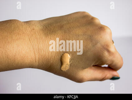 Bürste mit einem Tropfen klanglichen Mittel, die Hand auf einen weißen Hintergrund mit grünem Lack auf den Nagel... Stockfoto